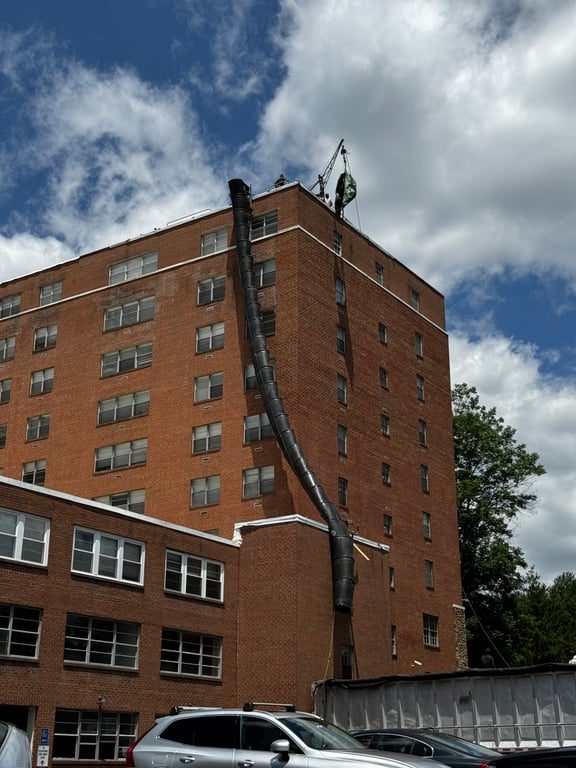 A building with a makeshift trash can slide down the side